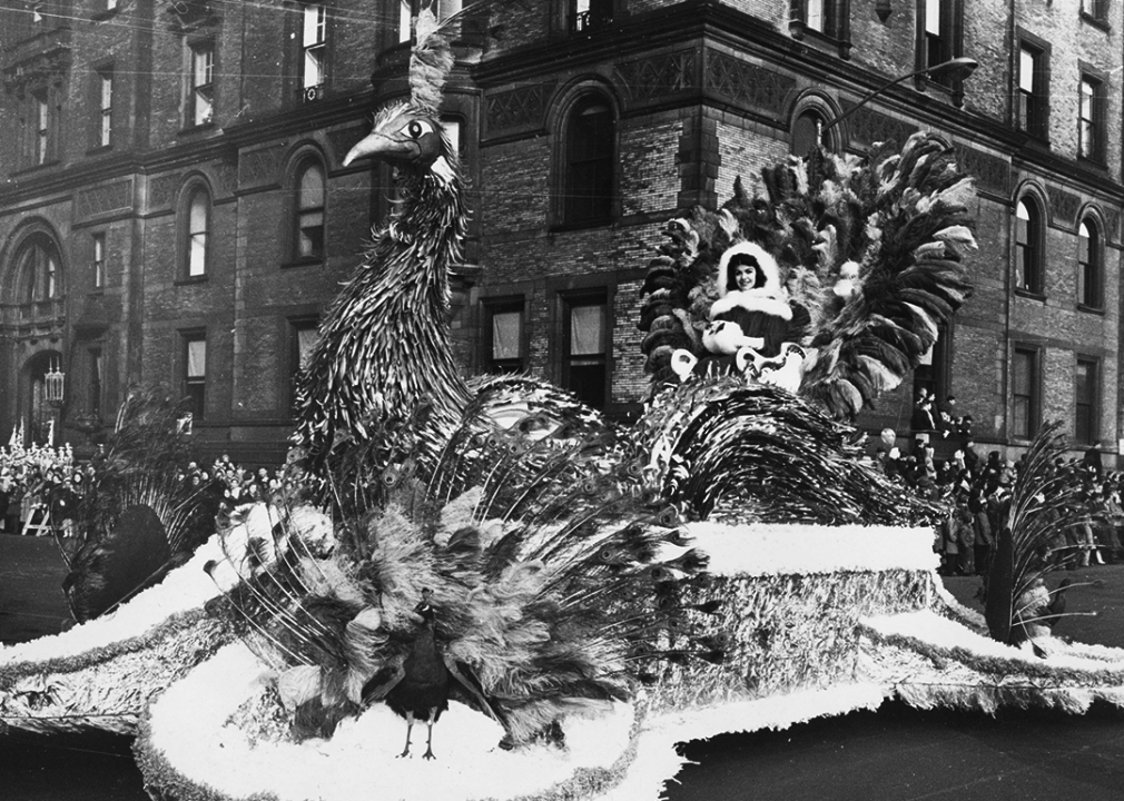 A woman sits on a peacock float in the parade.